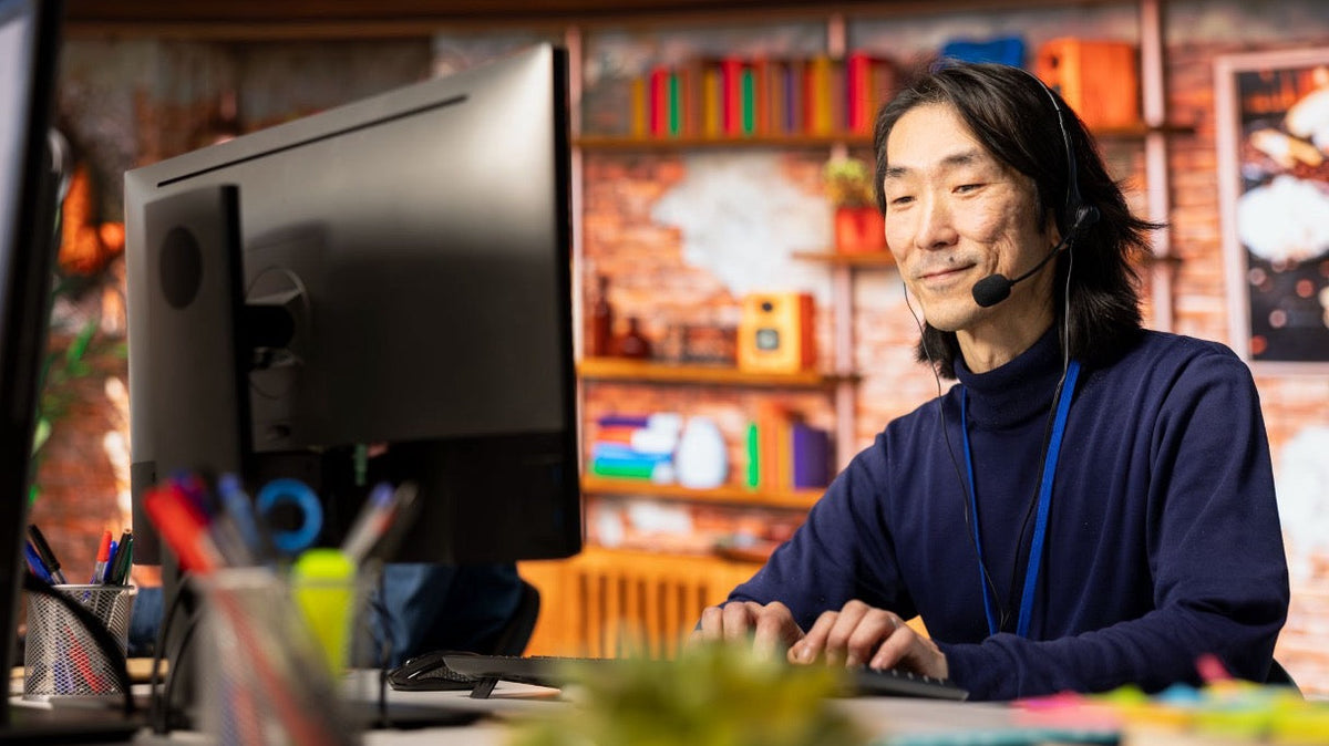 A Virtual Assistant wearing a headset assisting a client at a desktop computer