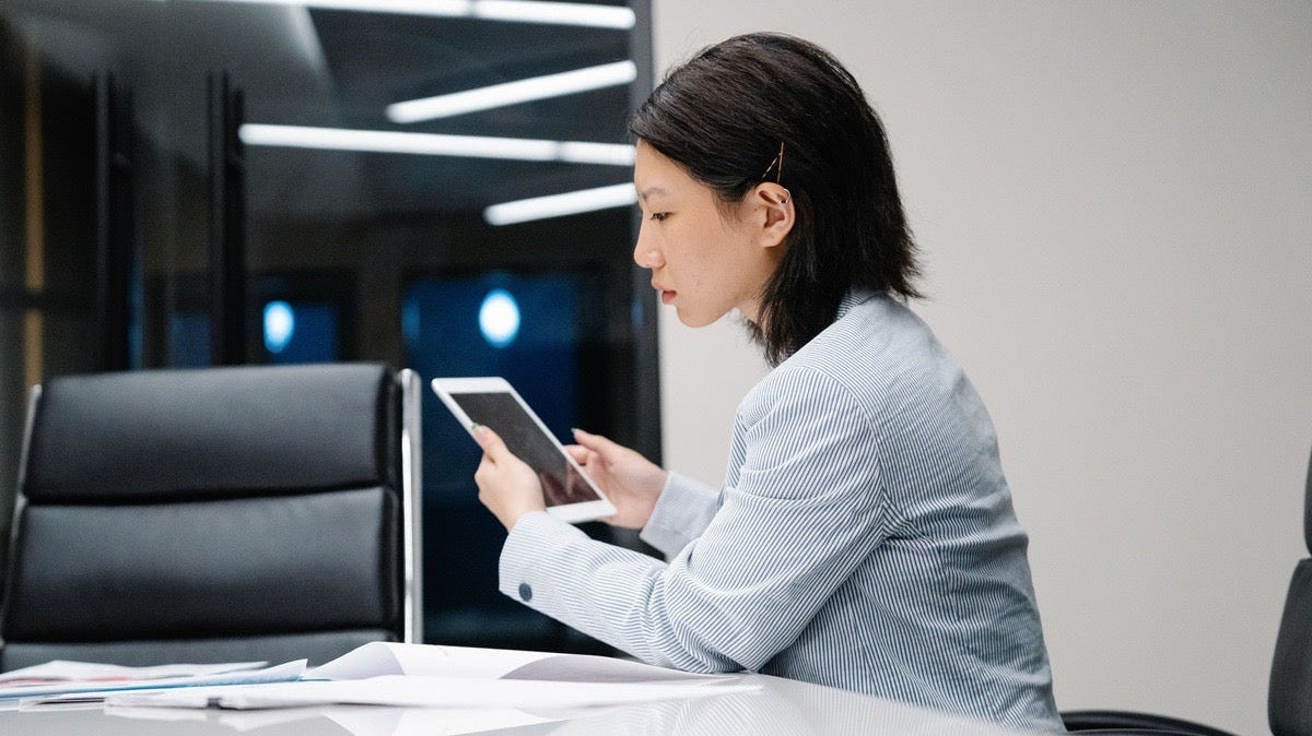 Education virtual assistant reviewing student records and schedules on a tablet from her workstation.