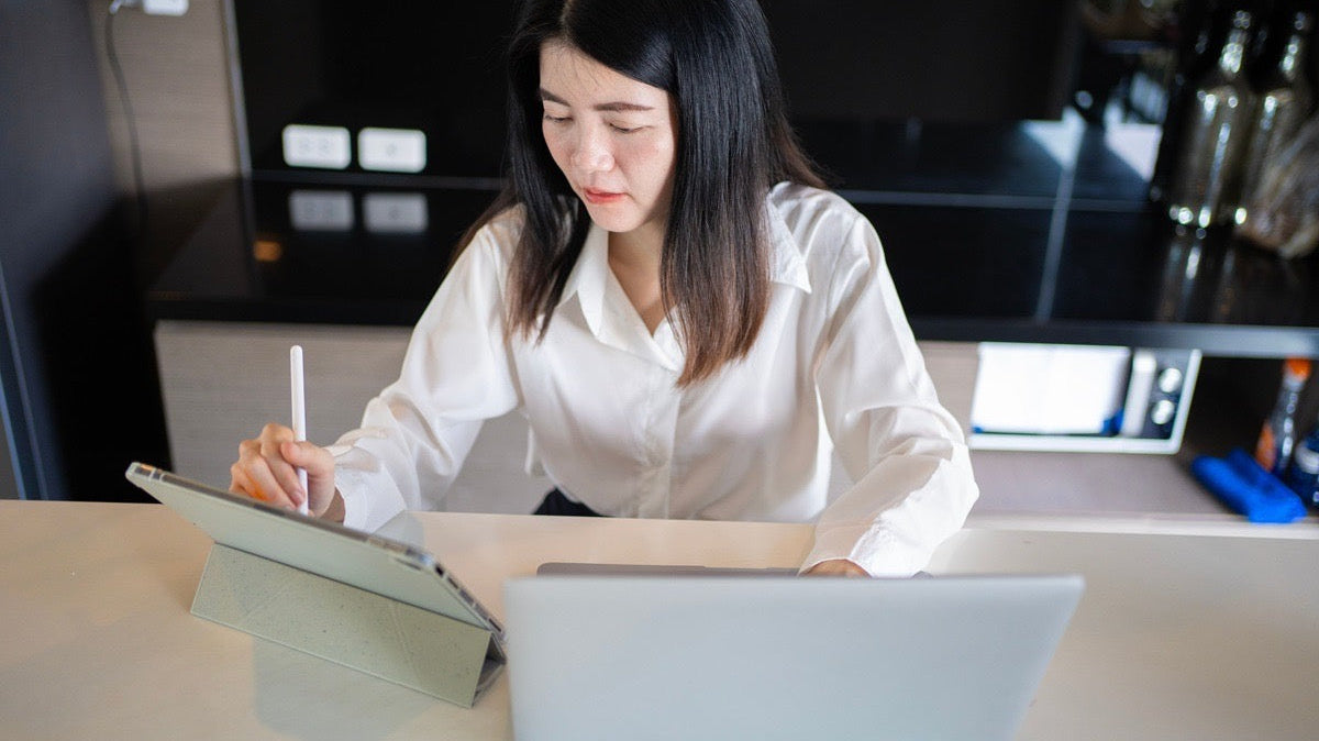 Scheduling virtual assistant updating client appointments on a tablet at her workstation.