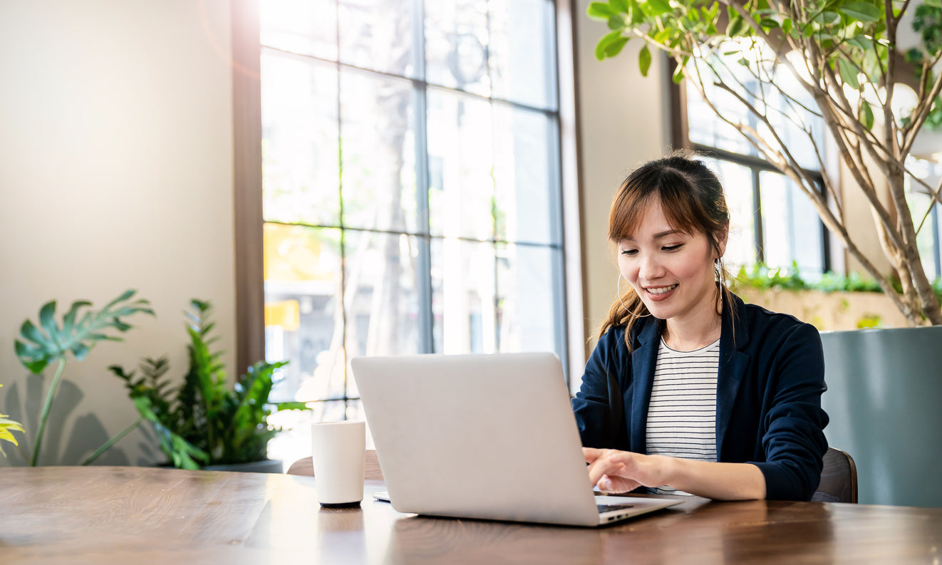 Businesswoman managing franchise finances remotely on a laptop in a bright office