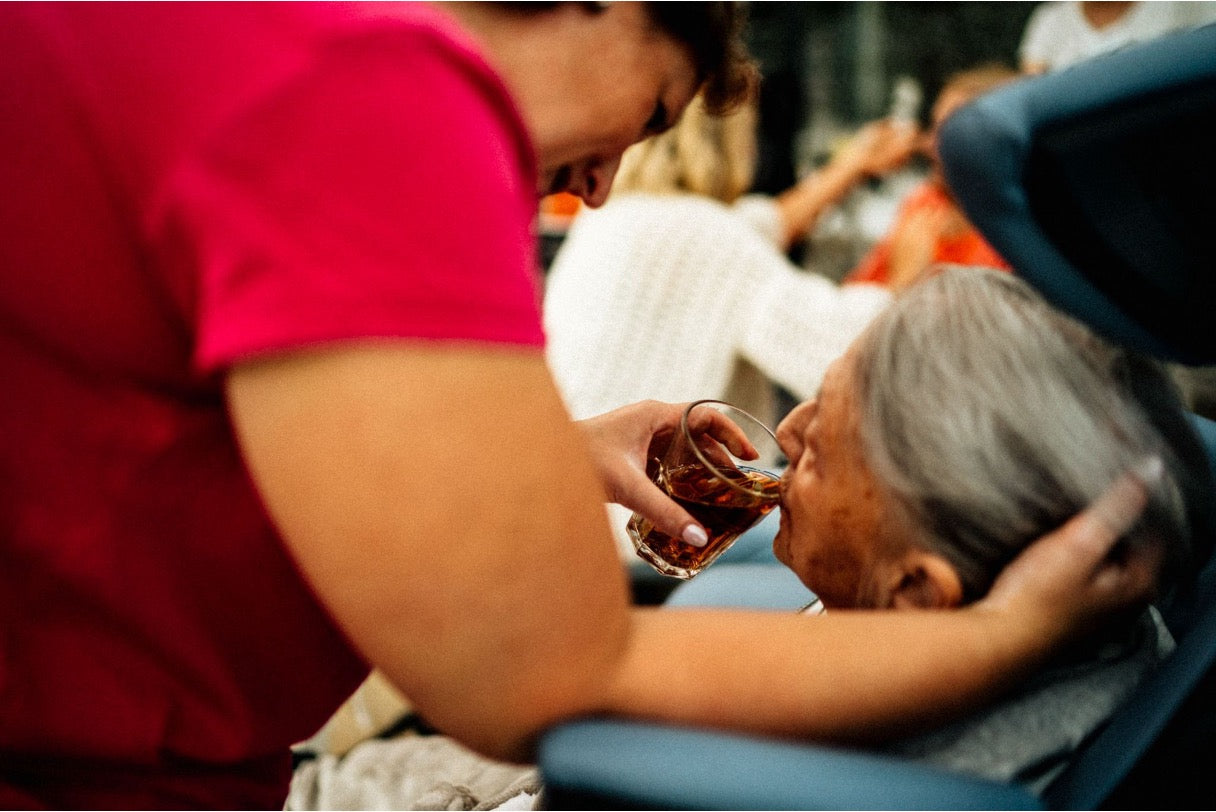 Caregiver helping an elderly woman drink tea