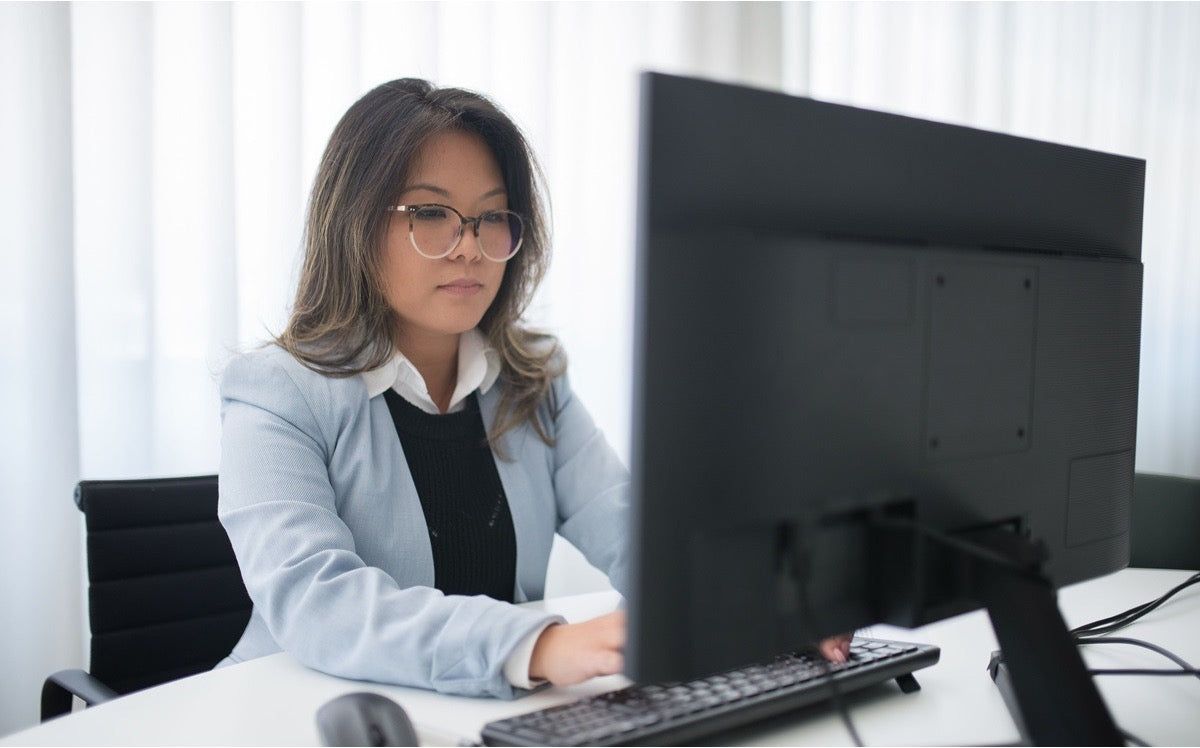 Data entry virtual assistant working at a desktop computer in a professional office setting