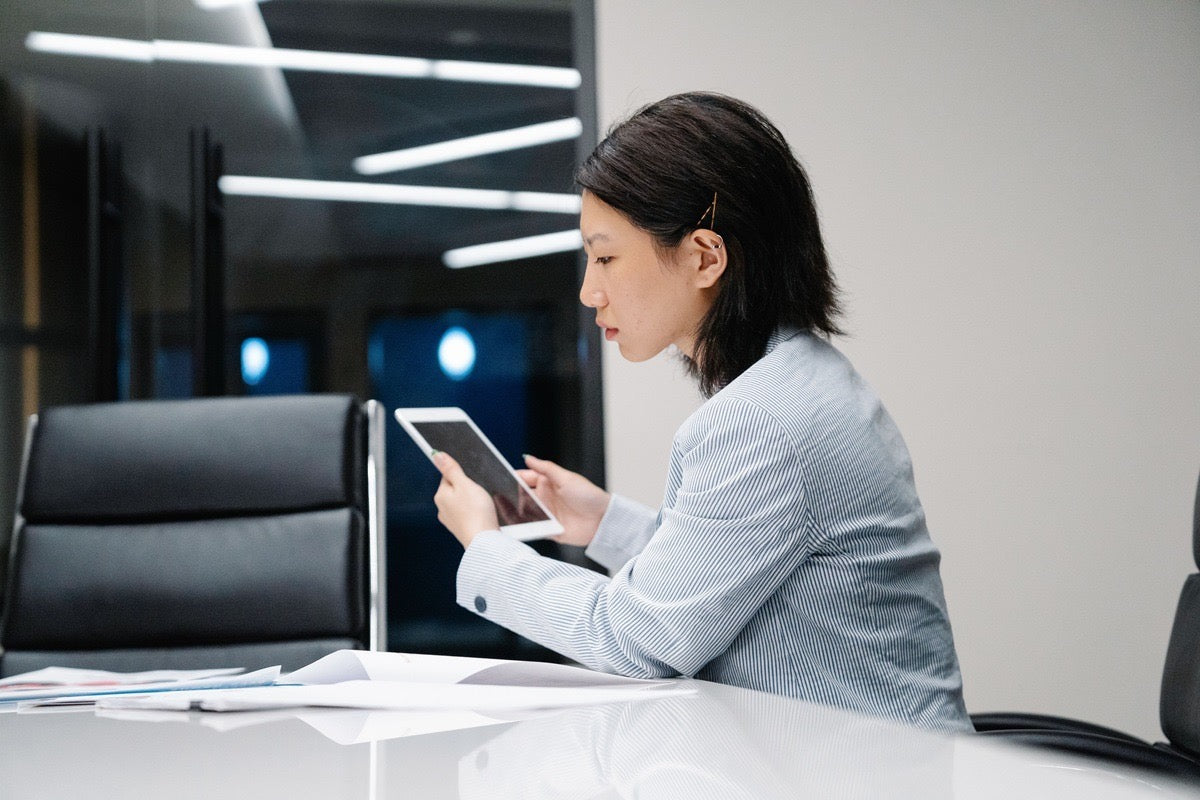 Education virtual assistant reviewing student records and schedules on a tablet from her workstation.
