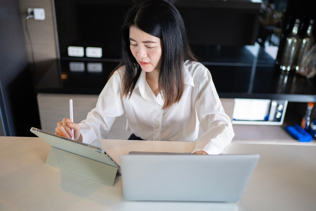 Scheduling virtual assistant updating client appointments on a tablet at her workstation.