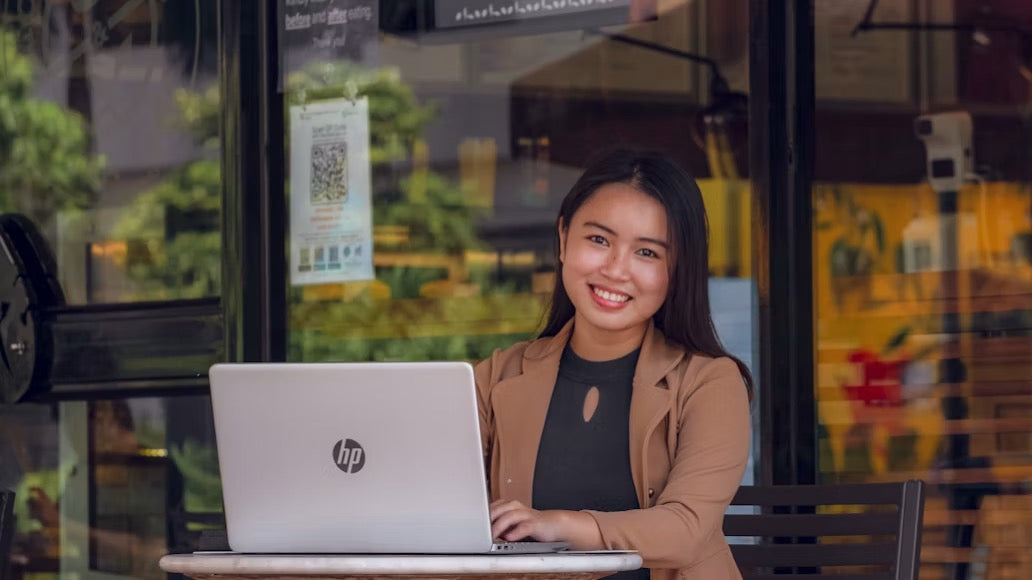 Woman smiling at the camera with her hands on her laptop keyboard